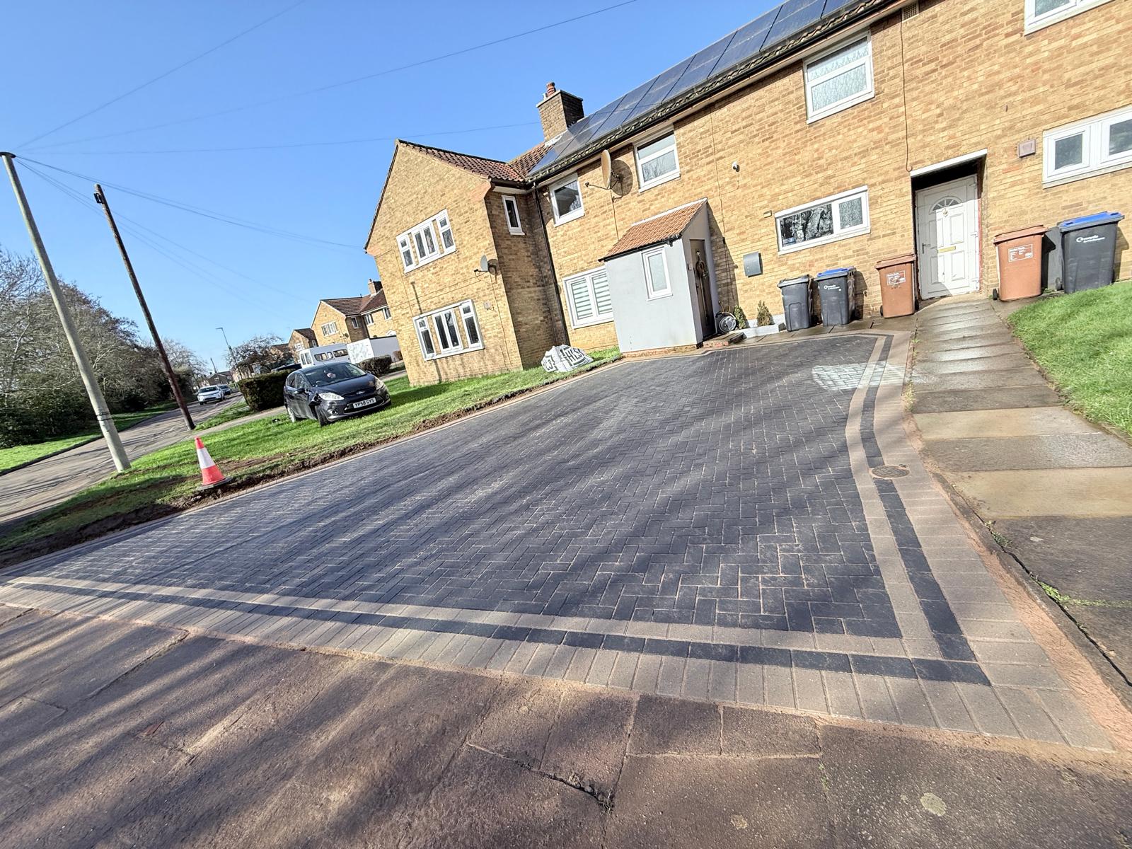 Low-angle wide view of the completed 65m² charcoal block paving driveway and front path integration on Windbrush Way, Northampton by AAS Group Construction