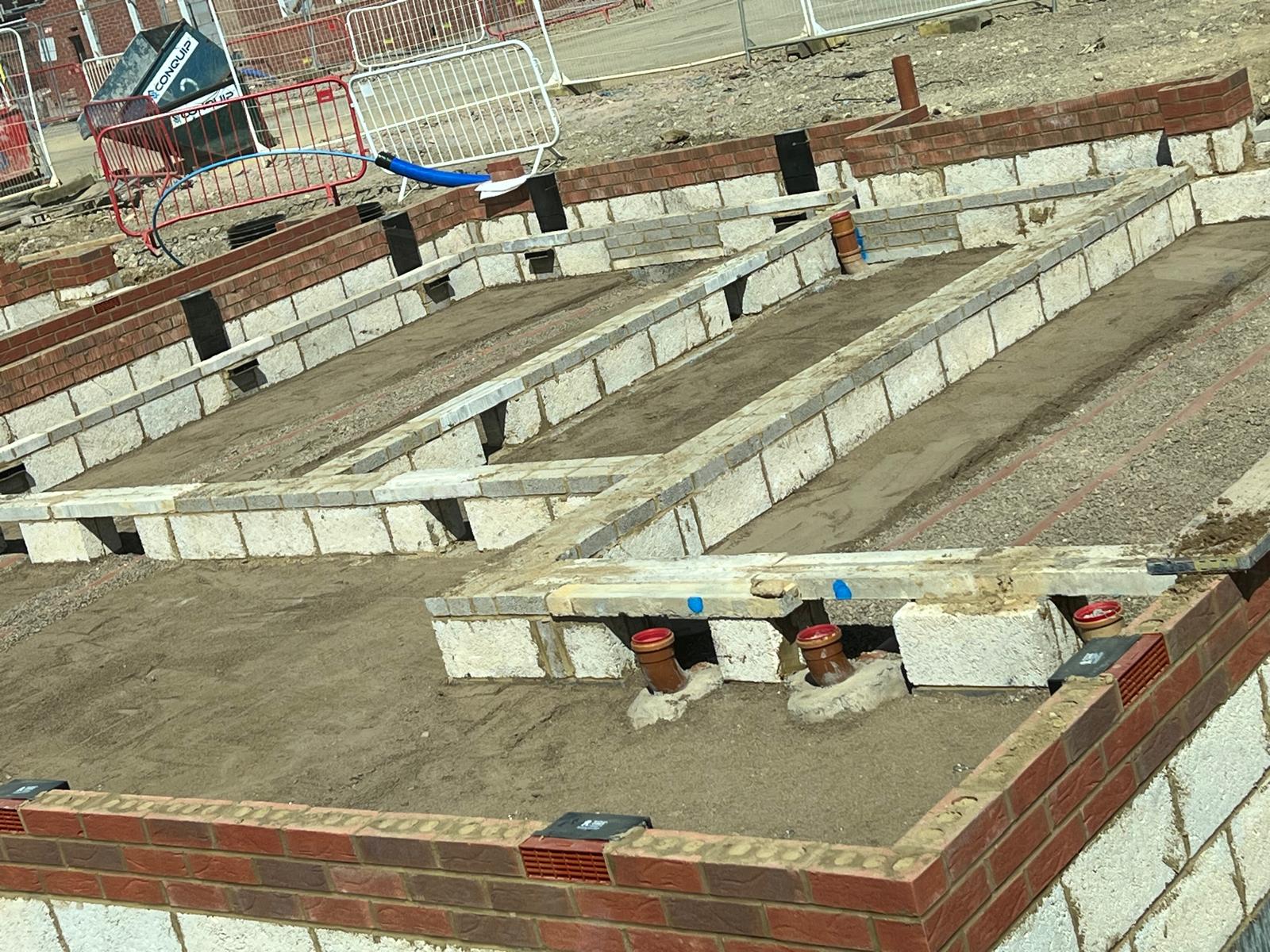 Completed house foundation substructure brickwork with drainage pipes and telescopic air vents in Wellingborough Northamptonshire